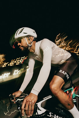 Cyclist rides through the night with blurred lights.