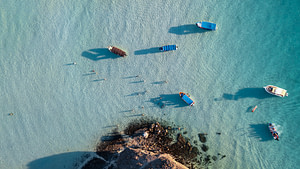 Boats float in beautiful, clear blue water.