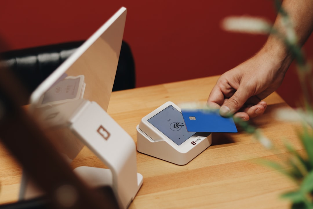 A person holding a credit card near a laptop