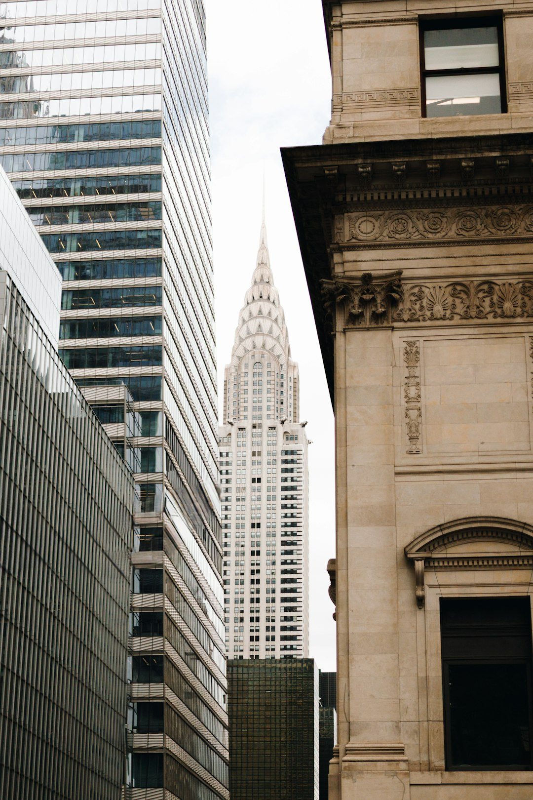 The chrysler building is framed by other buildings.